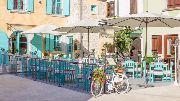 A café with outdoor seating, turquoise chairs, and white umbrellas. - Heritage hotel Chersin (Fazana)