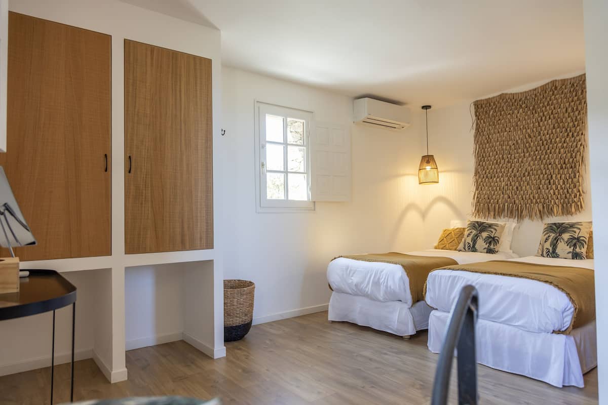 A bedroom with two beds, a desk, and a hanging light fixture.