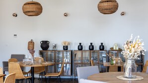 Un comedor con sillas de mimbre, una mesa redonda de madera y un jarrón con flores.