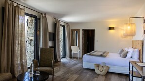 Un dormitorio con una cama, una silla, una mesa y una lámpara.