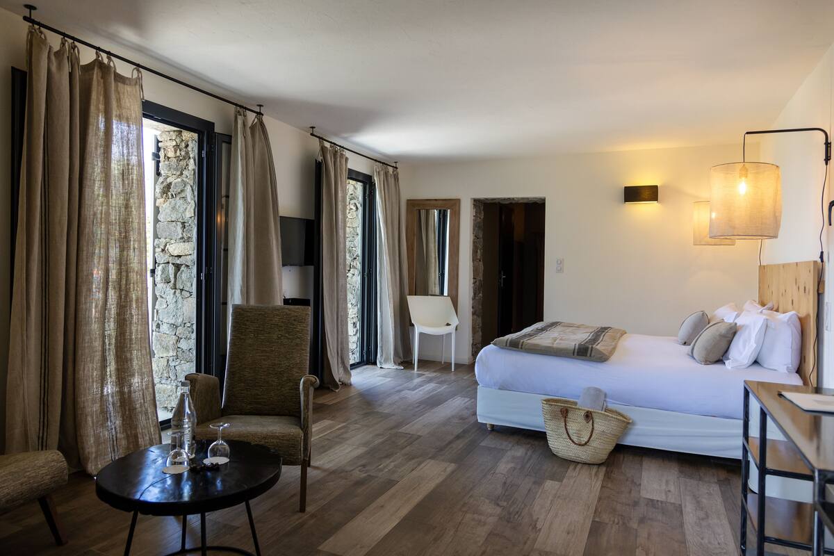 A bedroom with a bed, a chair, a table, and a lamp.
