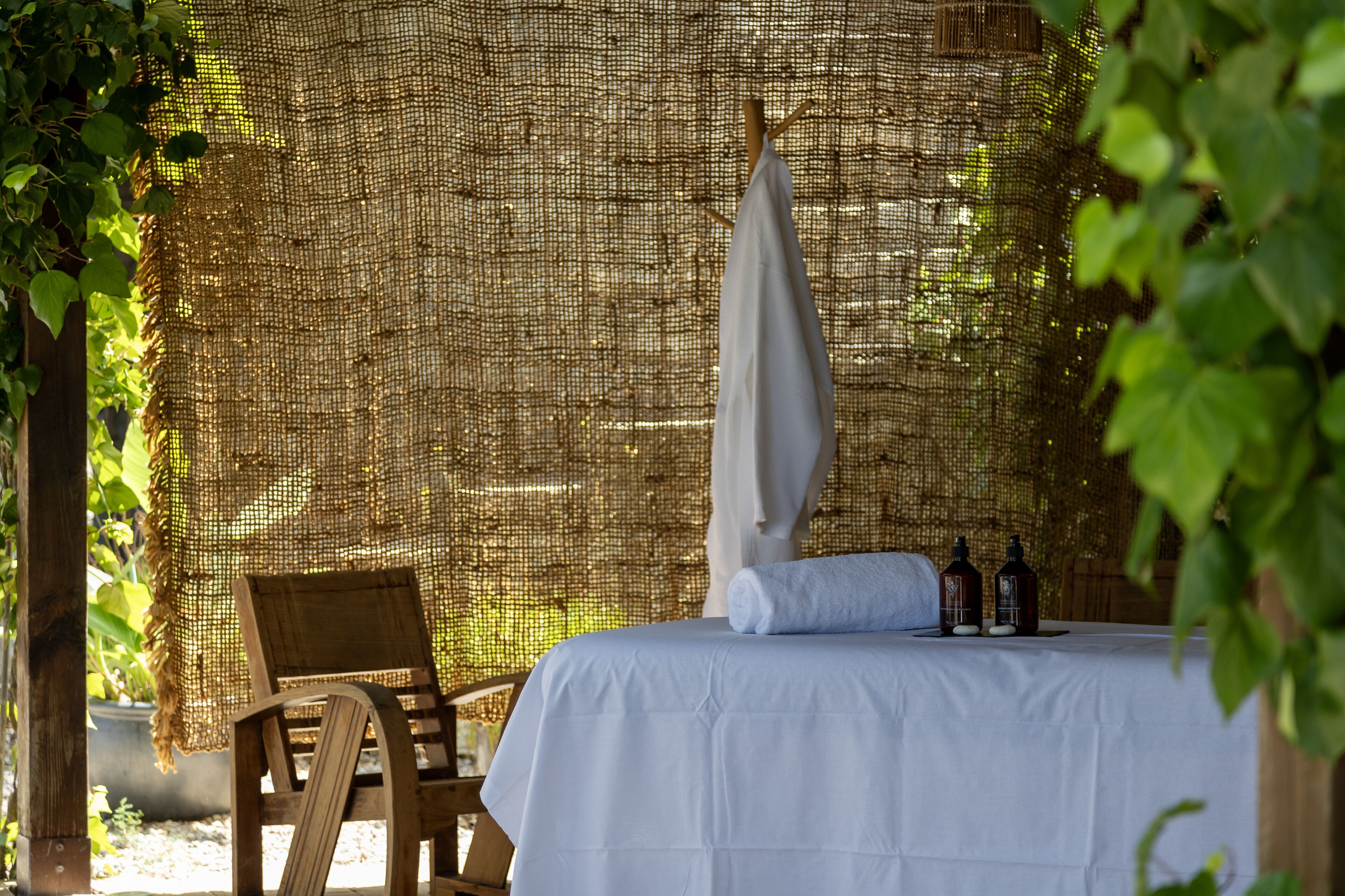 A room with a bed, a chair, and two bottles on the bed.
