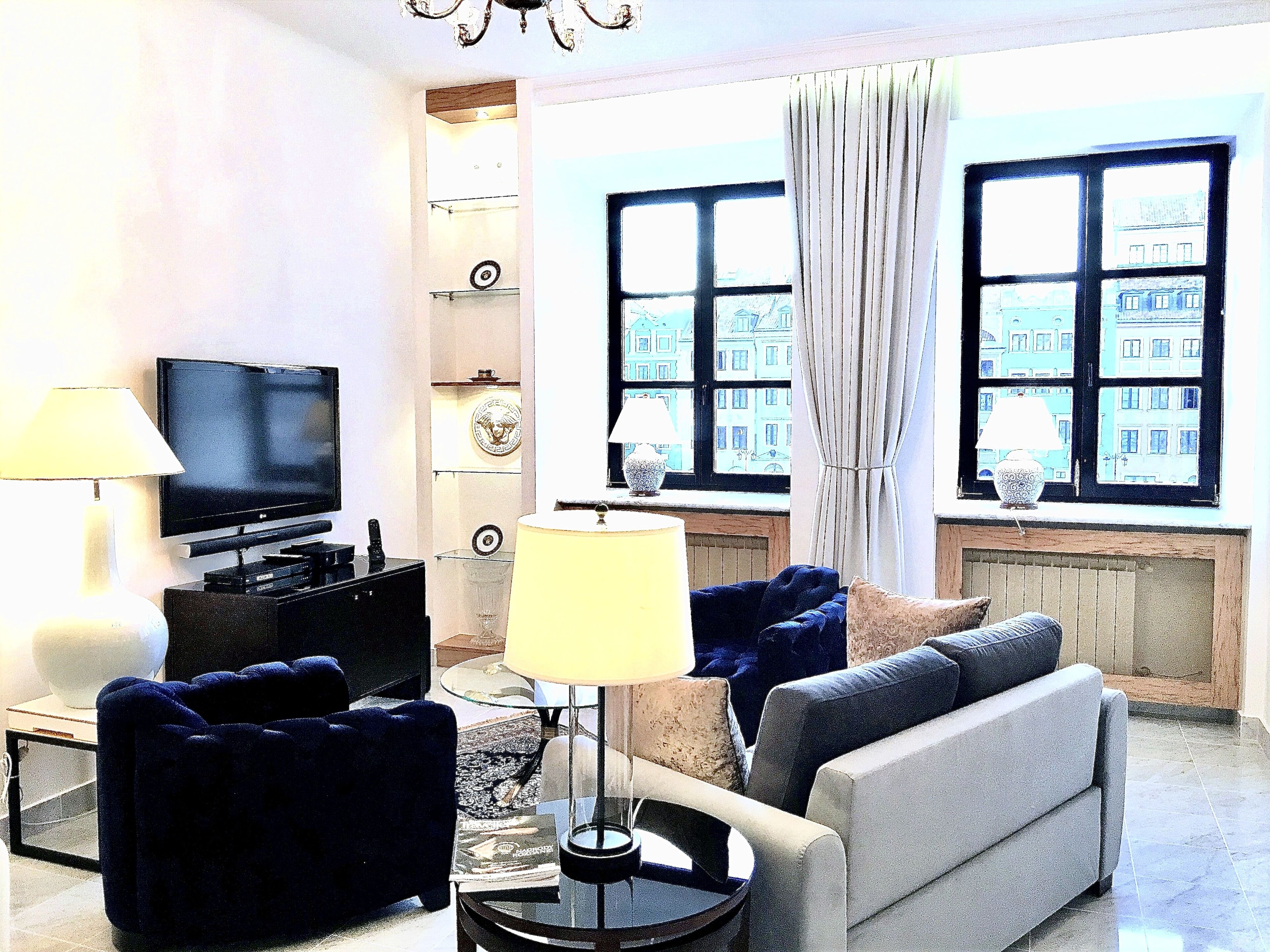 Een woonkamer met een flatscreen televisie, twee banken, een salontafel en een lamp.