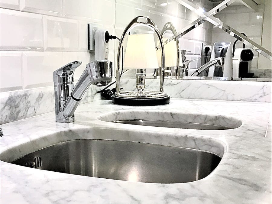 A modern bathroom with two sinks, a mirror, and a towel rack.