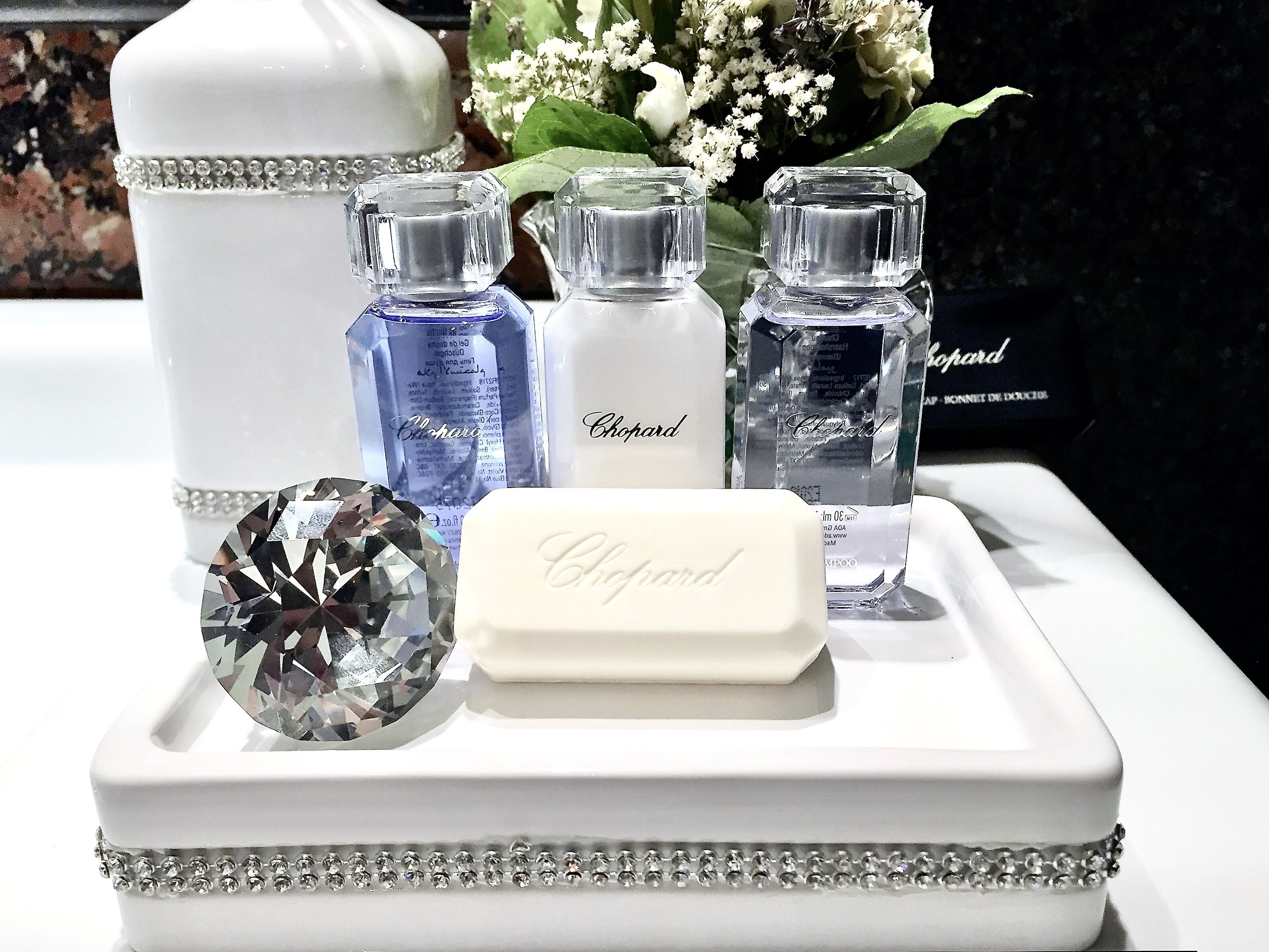 A display of Chopard perfume bottles and a diamond on a white tray.