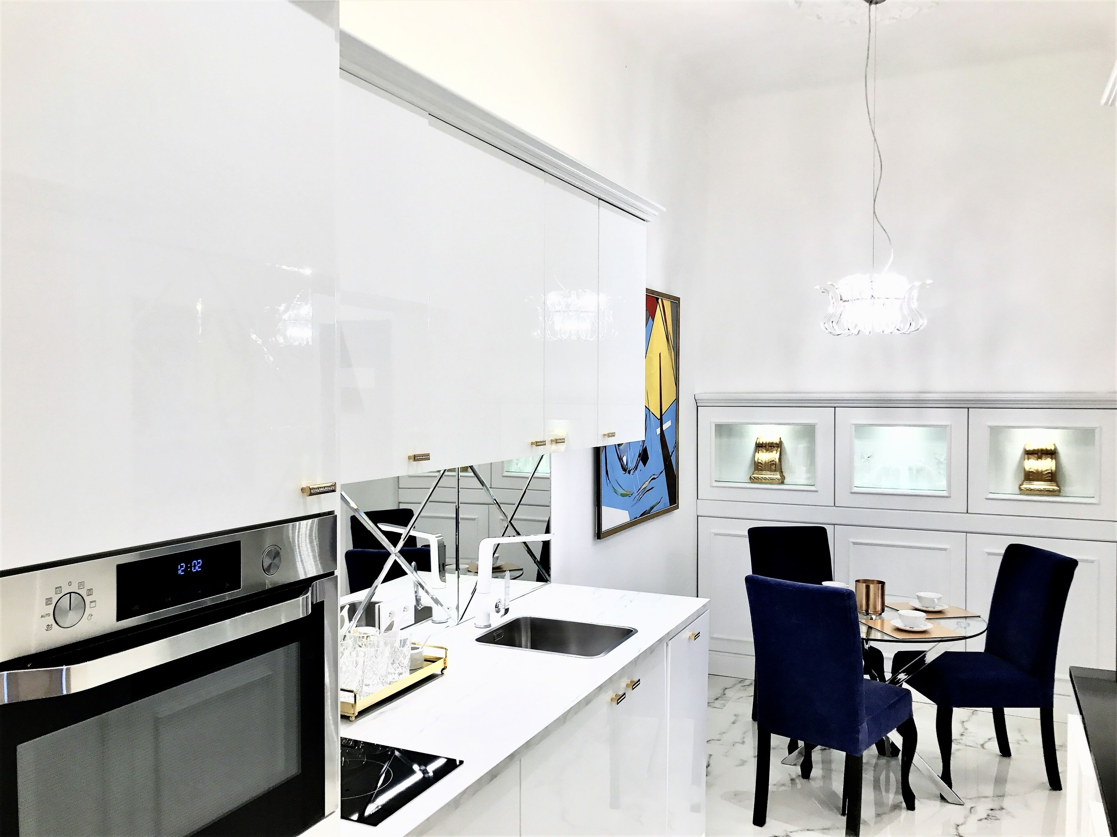 Una cocina moderna con horno empotrado, reloj digital y encimera blanca.