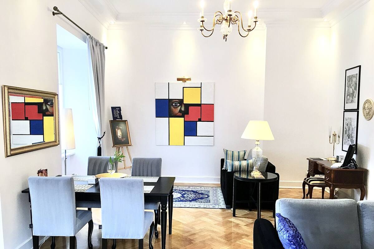 Una sala de estar moderna con comedor, que incluye una araña, obras de arte y un sofá.