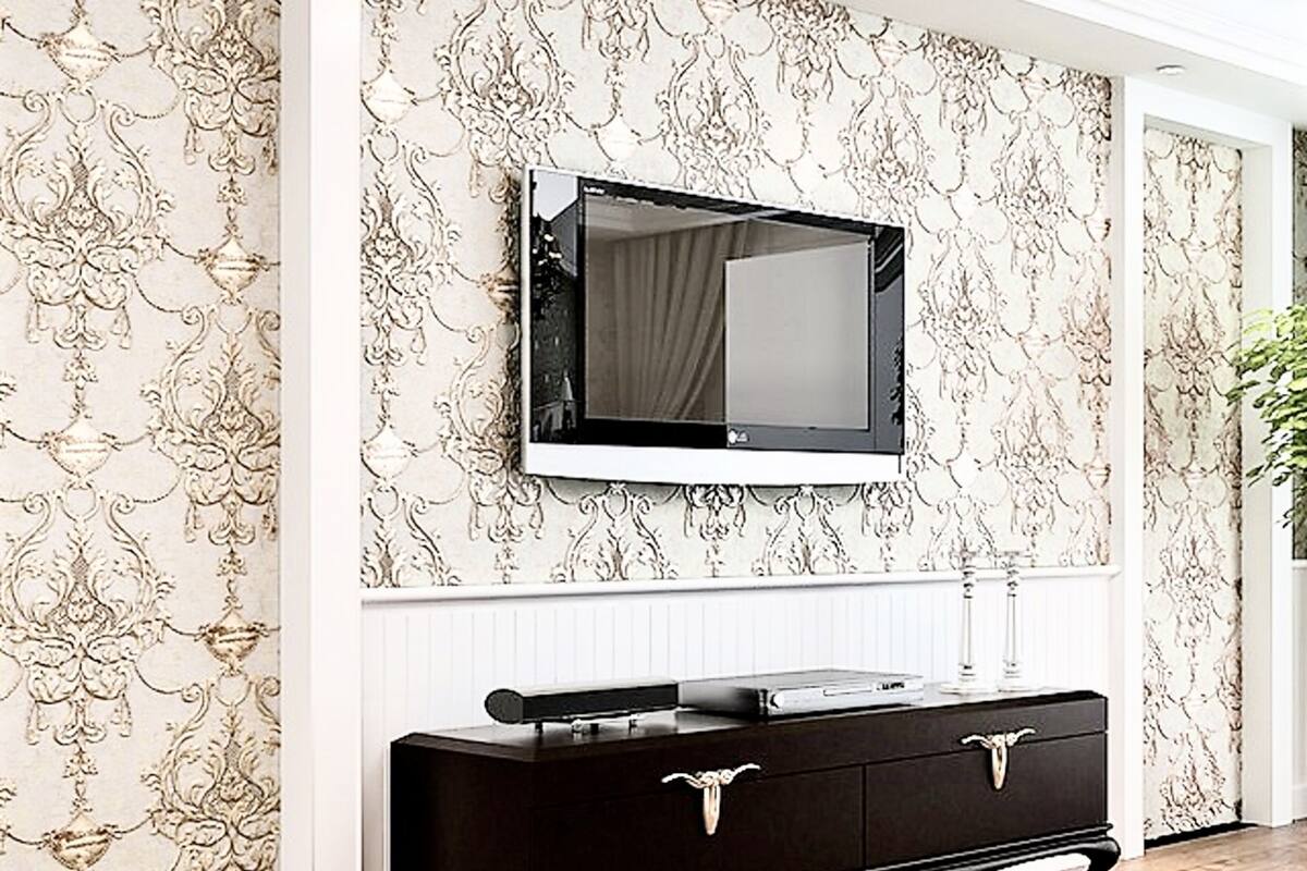 Una habitación con un espejo grande en la pared, un aparador de madera oscura y papel tapiz estampado.