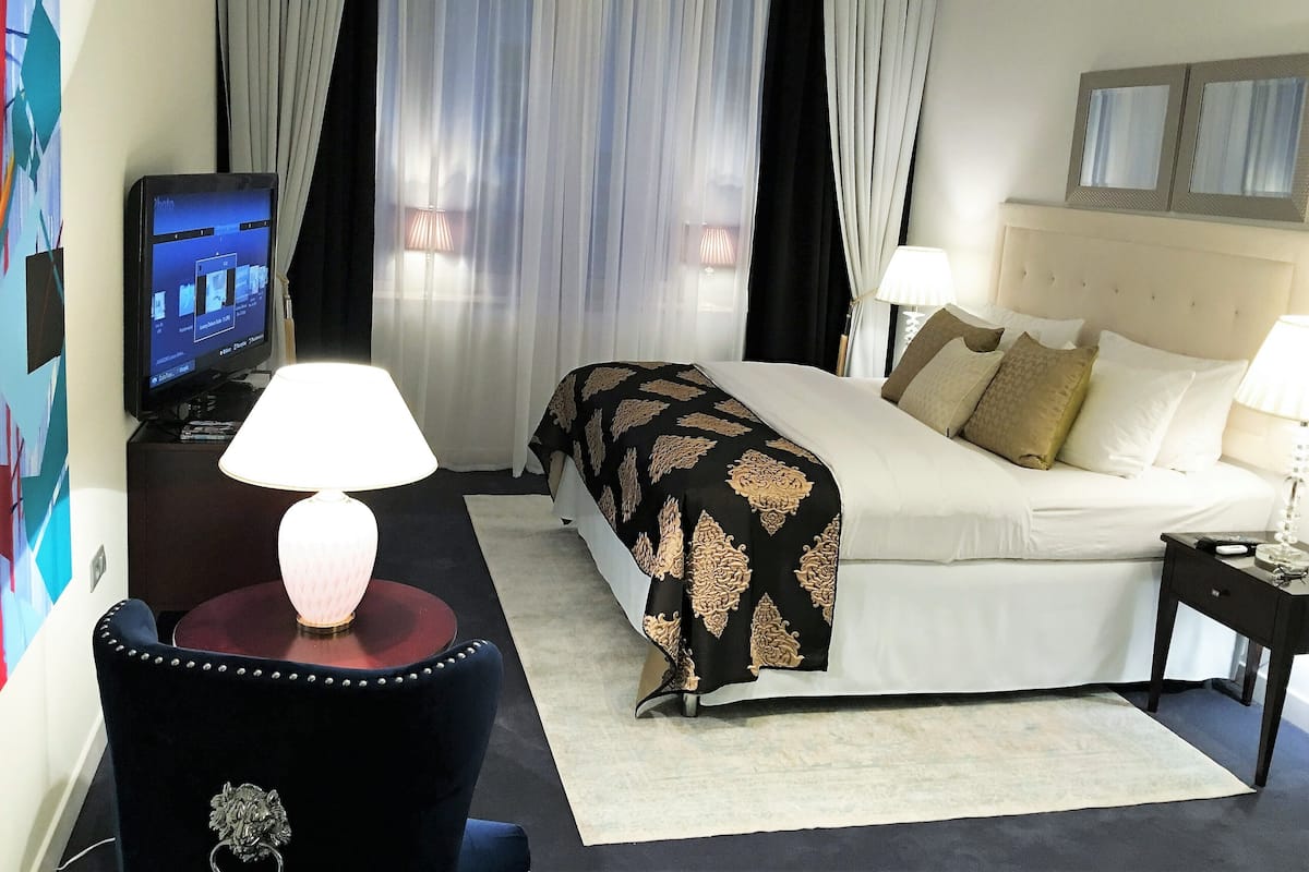 Una habitación de hotel con una cama, un escritorio con un ordenador, una lámpara y una silla.