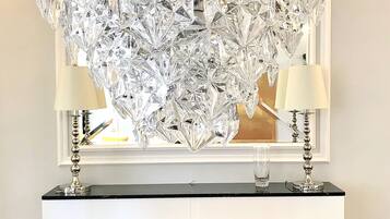 A chandelier made of clear crystal pieces hanging over a fireplace.