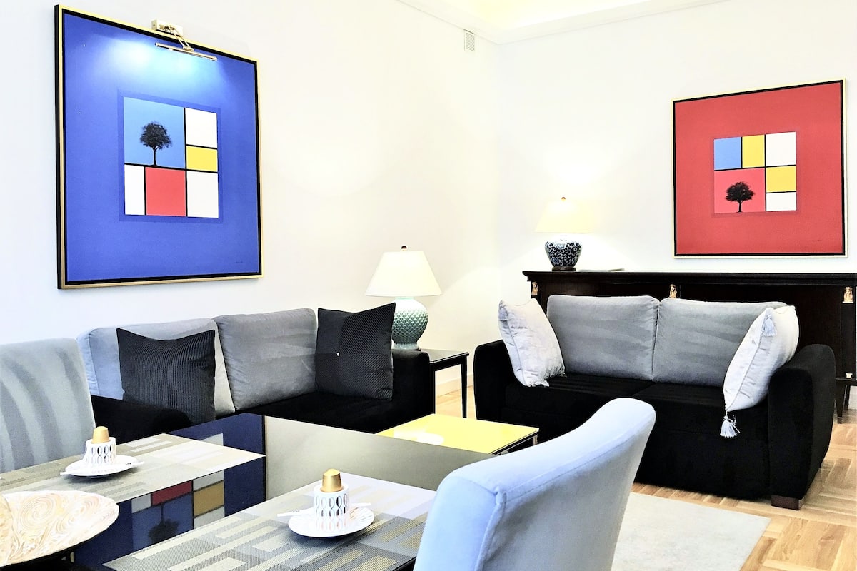 Una sala moderna con un sofá modular, una mesa de centro y dos obras de arte enmarcadas.