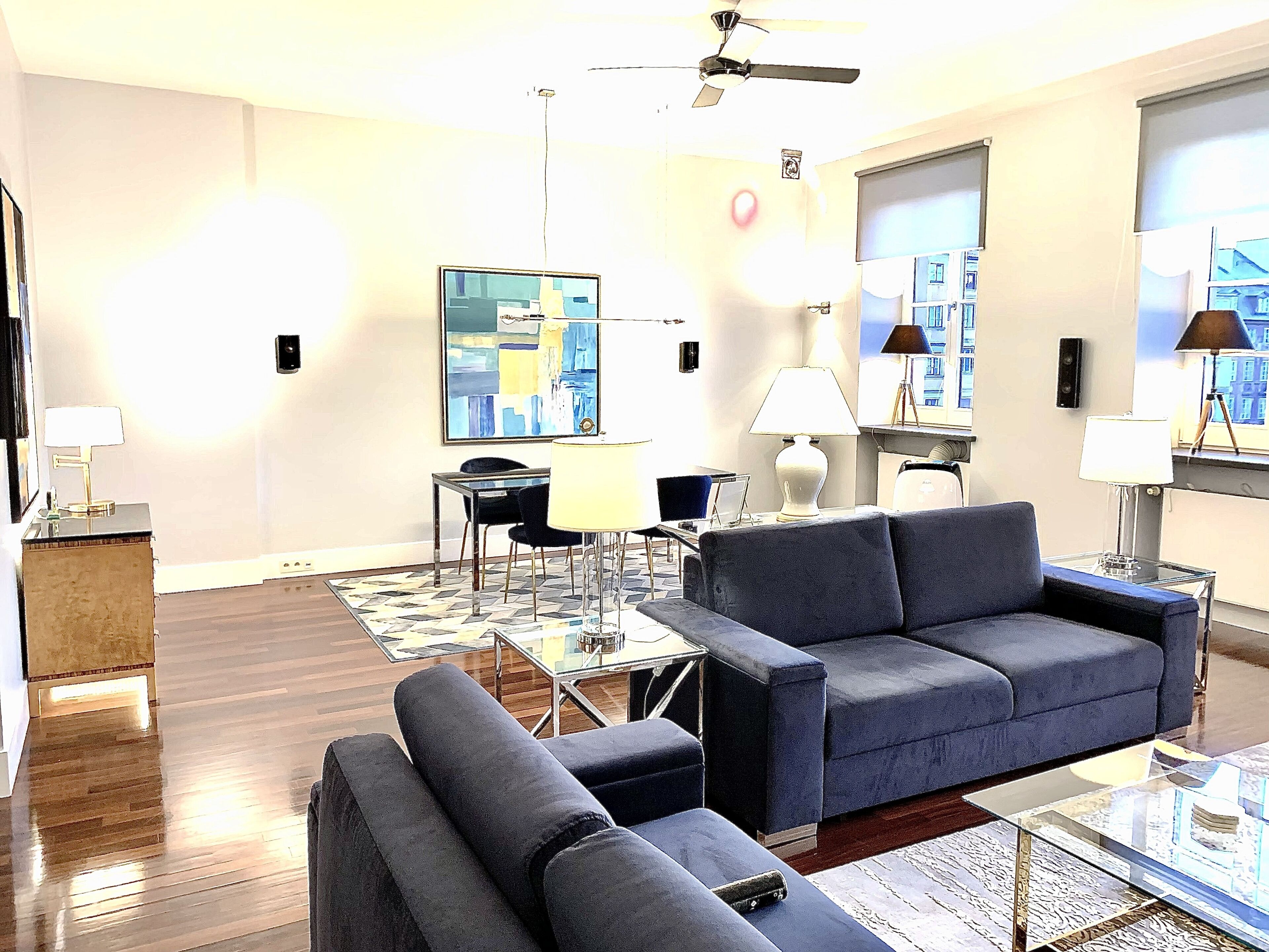 Una sala moderna con un sofá, sillones, una mesita de centro y un comedor con una mesa de vidrio y sillas.