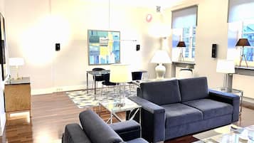 Una sala moderna con un sofá, sillones, una mesita de centro y un comedor con una mesa de vidrio y sillas.
