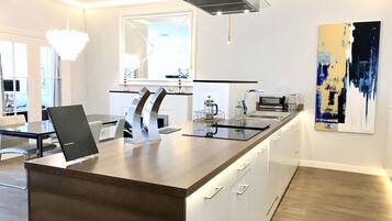 A modern kitchen with a central island, white cabinetry, and a large window.