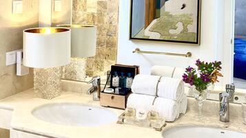 A bathroom with two sinks, a large mirror, a framed artwork, and a vase with flowers.