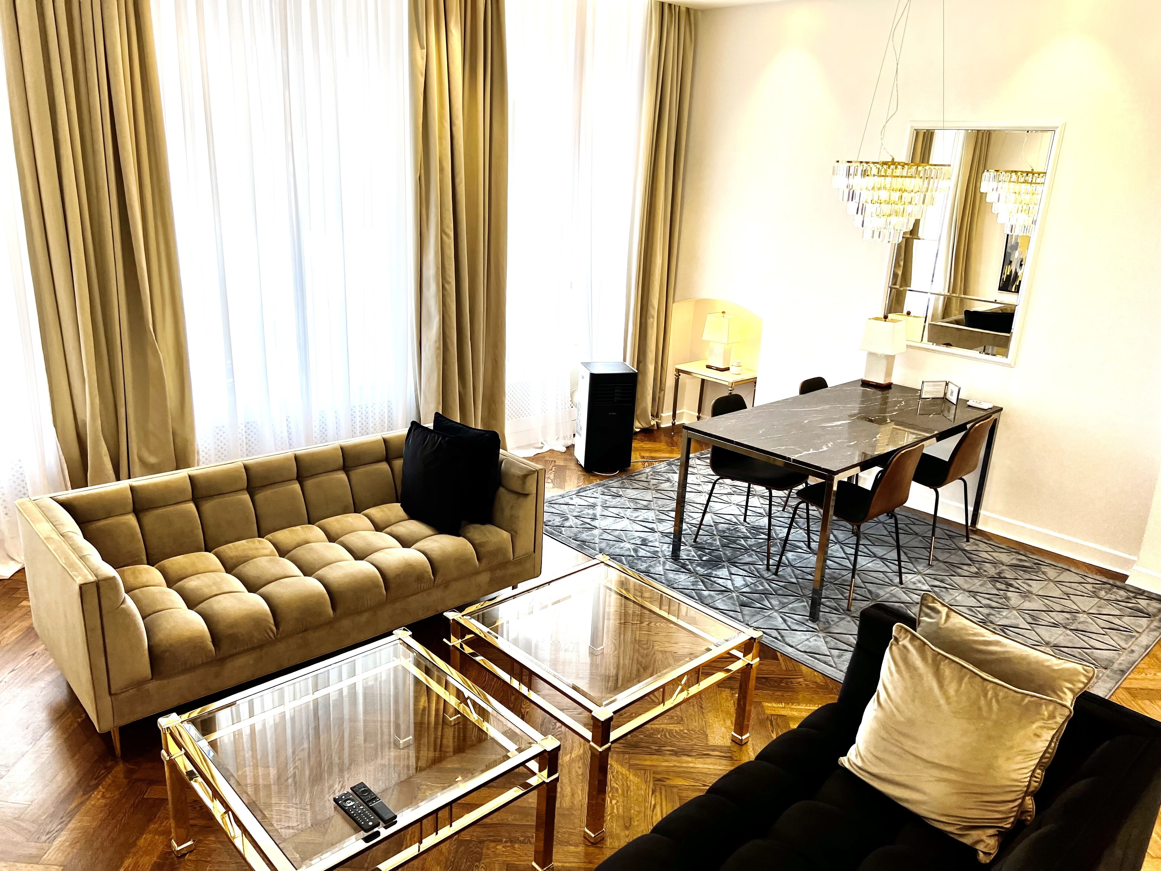 Ein Wohnzimmer mit einer Couch, zwei Couchtischen, einem Esstisch mit Stühlen und einem großen Spiegel.