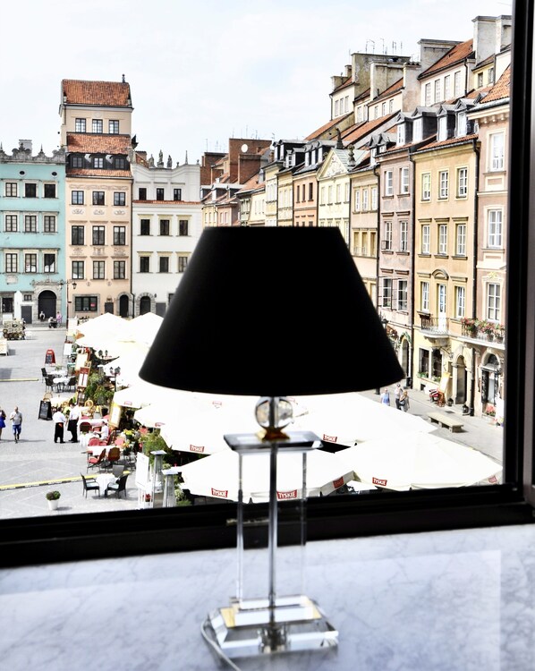 Uma luminária de mesa com base transparente e cúpula preta, apoiada em uma superfície de mármore.
