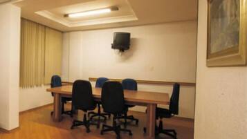 Une salle de conférence avec une longue table, six chaises, un téléviseur à écran plat fixé au mur et un tableau accroché au mur.