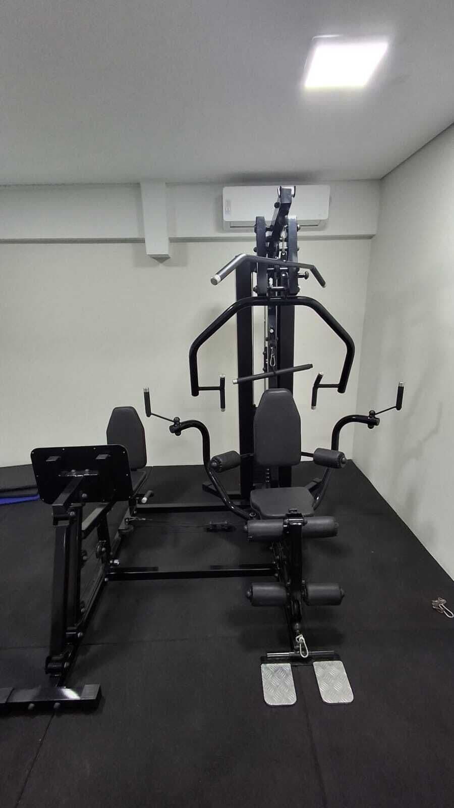 A gym with a multi-functional exercise machine, a bench, and a pull-up bar.