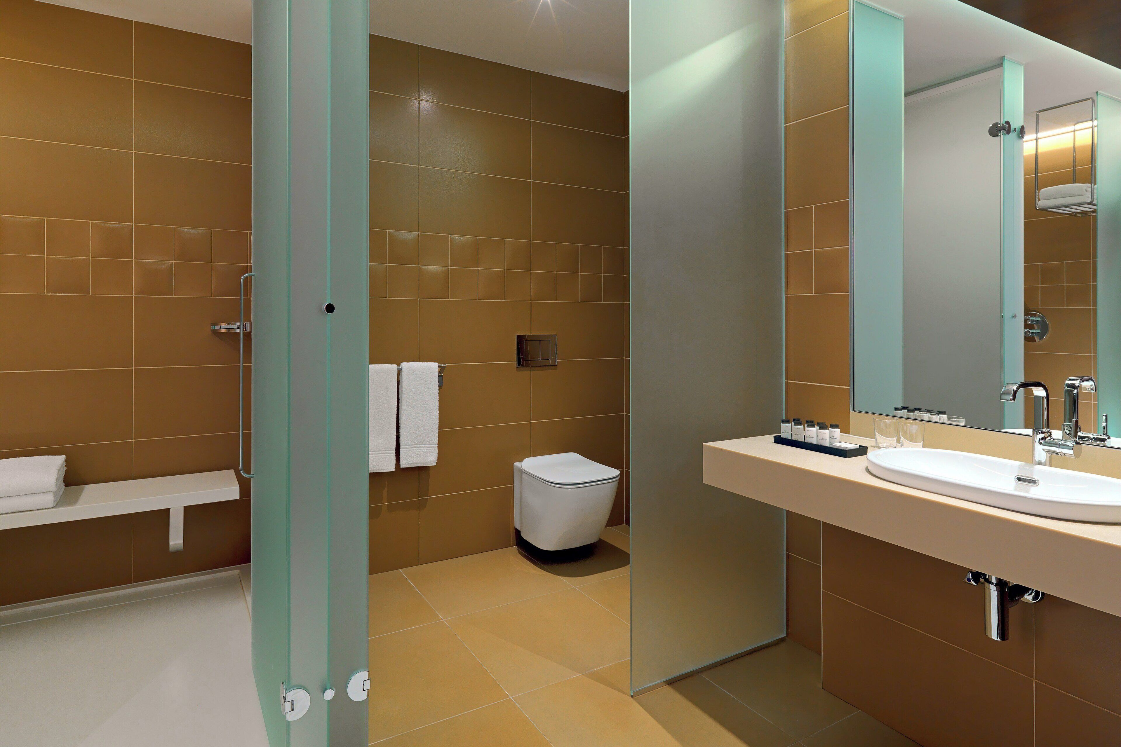 A modern bathroom with a glass shower enclosure, a white sink, and a mirror.