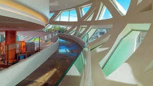A modern interior with a curved glass staircase, multiple levels, and large windows allowing natural light. - Sheraton Annaba Hotel (Annaba)