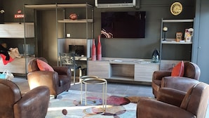 A modern living room with leather sofas, a coffee table, and a flat-screen TV mounted on the wall. - Hotel Saint Louis (Le Thor)