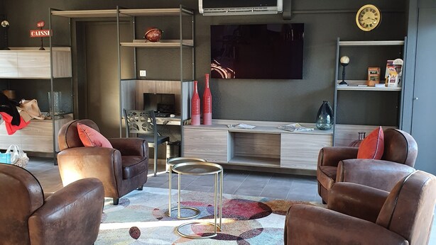 A modern living room with leather sofas, a coffee table, and a flat-screen TV mounted on the wall. - Hotel Saint Louis (Le Thor)
