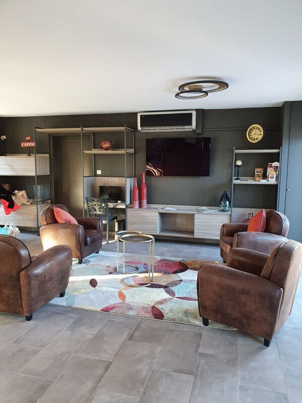 A modern living room with leather sofas, a coffee table, and a flat-screen TV mounted on the wall.