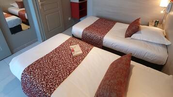 A hotel room with two beds, a TV mounted on the wall, a bedside table with a lamp, and a red storage unit.