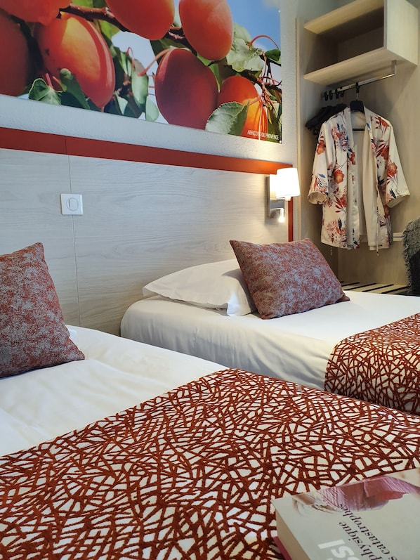 A hotel room with two beds, a wardrobe, and a wall-mounted light. - Hotel Saint Louis (Le Thor)