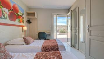 Habitación de hotel con dos camas, un escritorio y vistas a través de un ventanal.