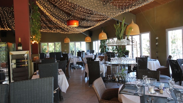 A restaurant with wicker furniture, string lights, and a variety of table settings. - Hotel Saint Louis (Le Thor)