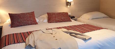 Ein Hotelzimmer mit einem Bett, zwei Kissen, einem Nachttisch mit Lampe, einem Telefon und einem Koffer.