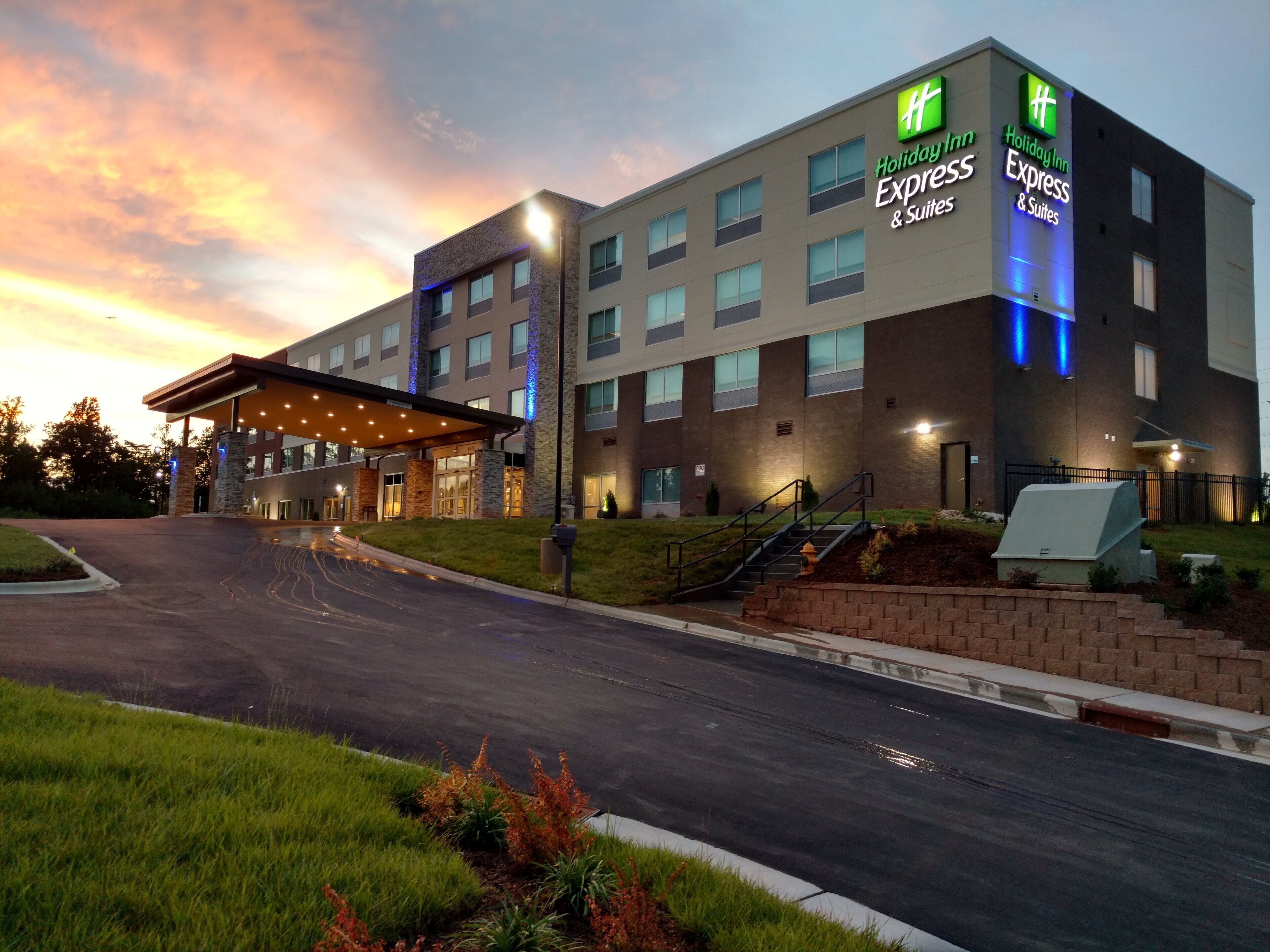 Edificio de Holiday Inn Express & Suites con entrada cubierta, varias ventanas y fachada bien iluminada.