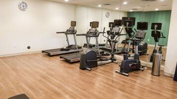 A gym with multiple treadmills, elliptical machines, and a bench.