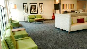 A modern lobby with green and white seating, framed artwork on the walls, and a flat-screen TV.