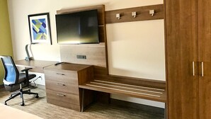 A modern bedroom with a wooden desk, a TV mounted on the wall, a wardrobe, and a framed picture. - Holiday Inn Express & Suites Charlotte NE - University Area by IHG (Charlotte)