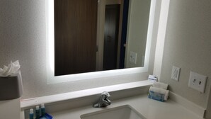 A bathroom with a large mirror, a sink, and a window. - Holiday Inn Express & Suites Charlotte NE - University Area by IHG (Charlotte)
