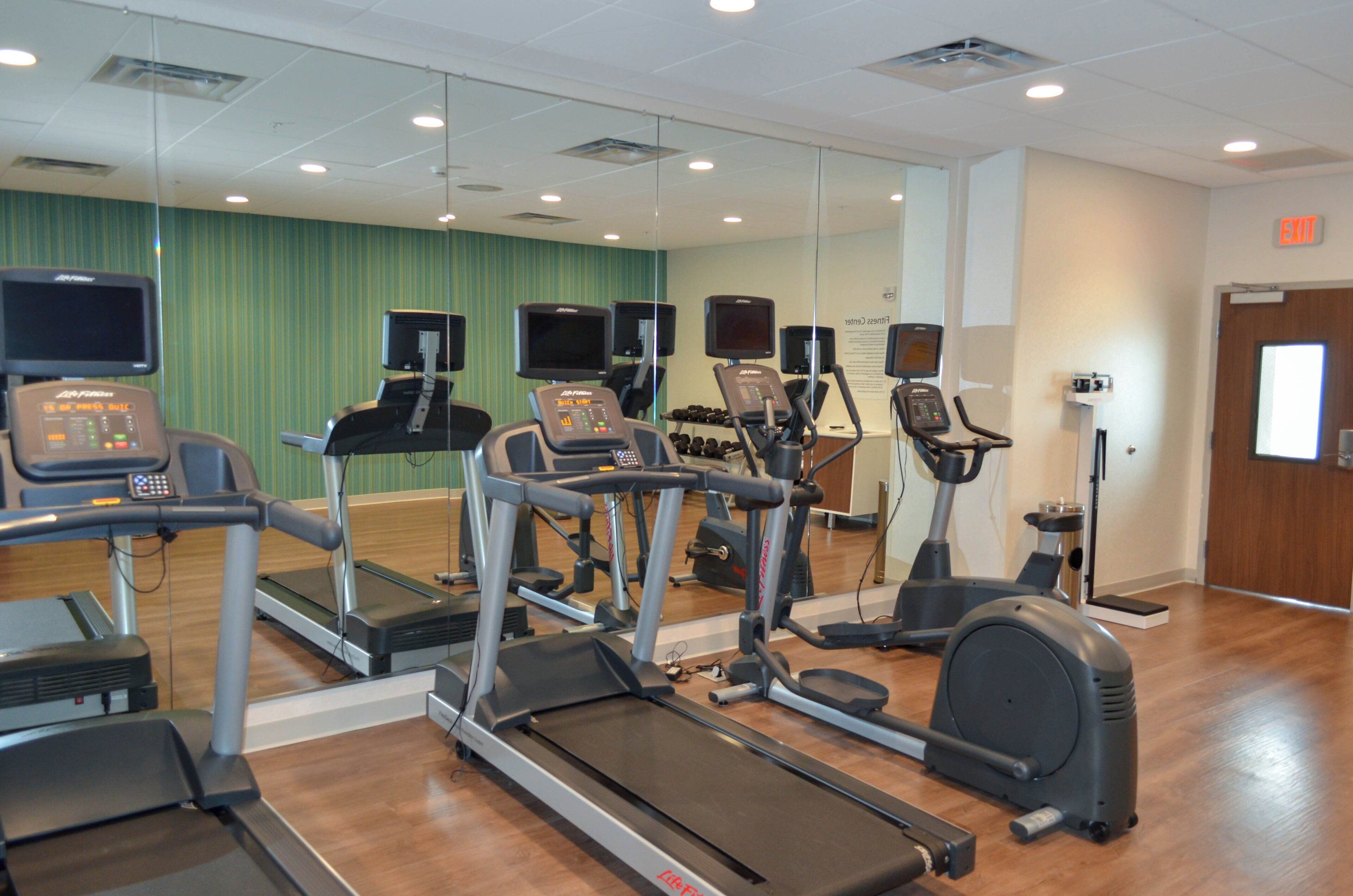 A gym with treadmills, elliptical machines, and stationary bikes.