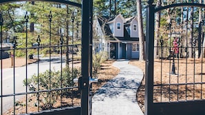 A gated driveway leading to a house with a sloped roof and a front porch. - Hogsveil Cottages - Harry Potter Themed (Eureka Springs)