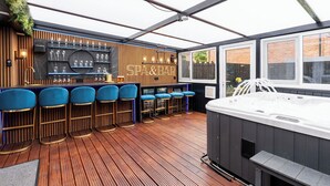 Zona de bar con mostrador de madera, taburetes azules, un jacuzzi y un cartel que dice "SPA & BAR".