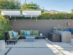 Relax in a serene outdoor space with a comfortable seating area, round table, and lush greenery.