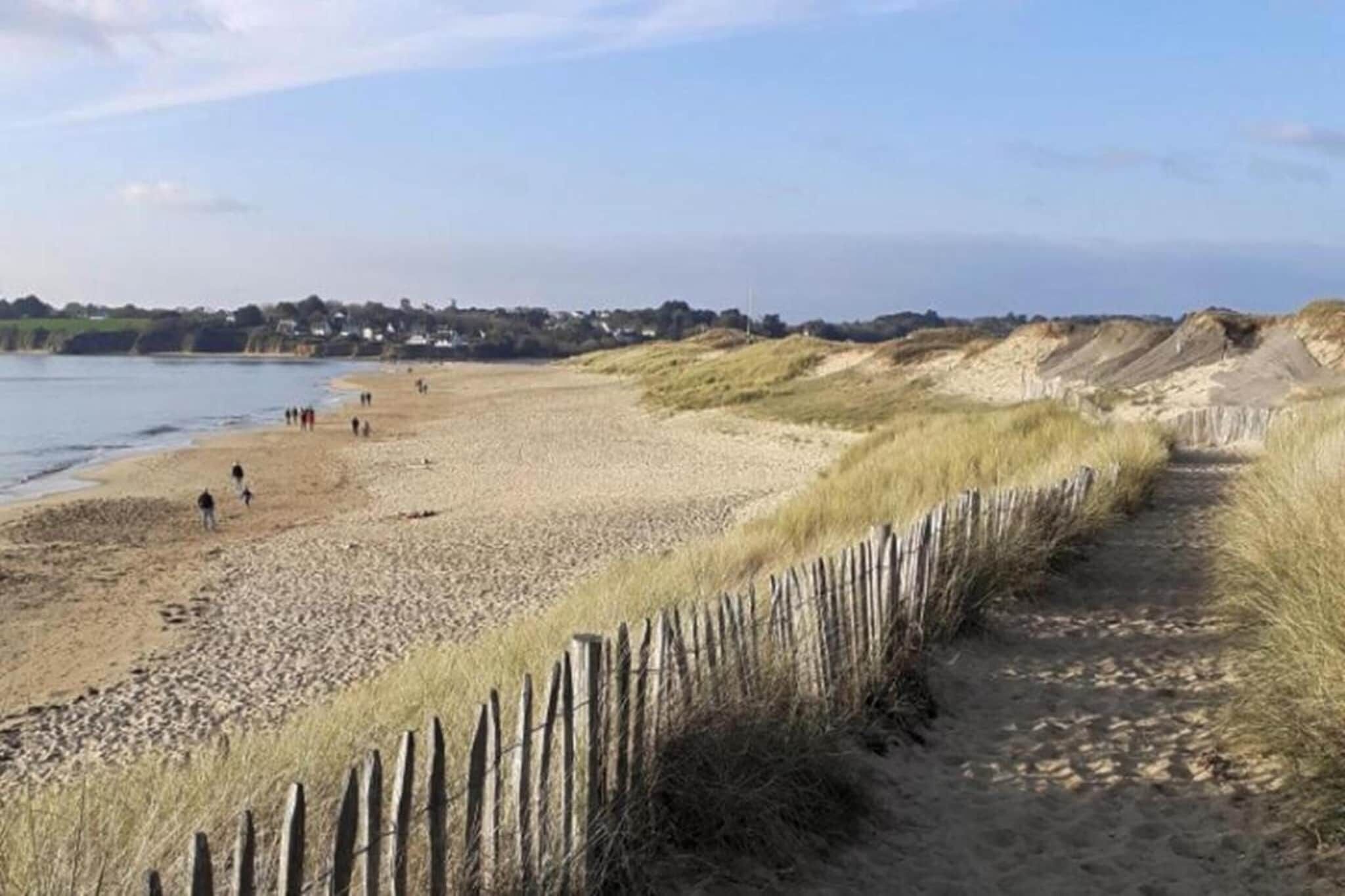 Una spiaggia sabbiosa con una recinzione in legno e un sentiero che conduce all'acqua.