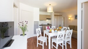 Een knus woongedeelte met eethoek, kitchenette en een bank.