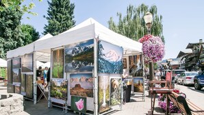 A tent with various paintings and a bench with flowers. - La Cabina (Leavenworth)
