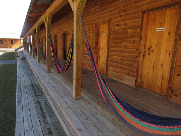 A wooden building with a porch, hammocks, and a sign reading 'CABANA 13'. - Godspeed Events & Lodging (Port Matilda)