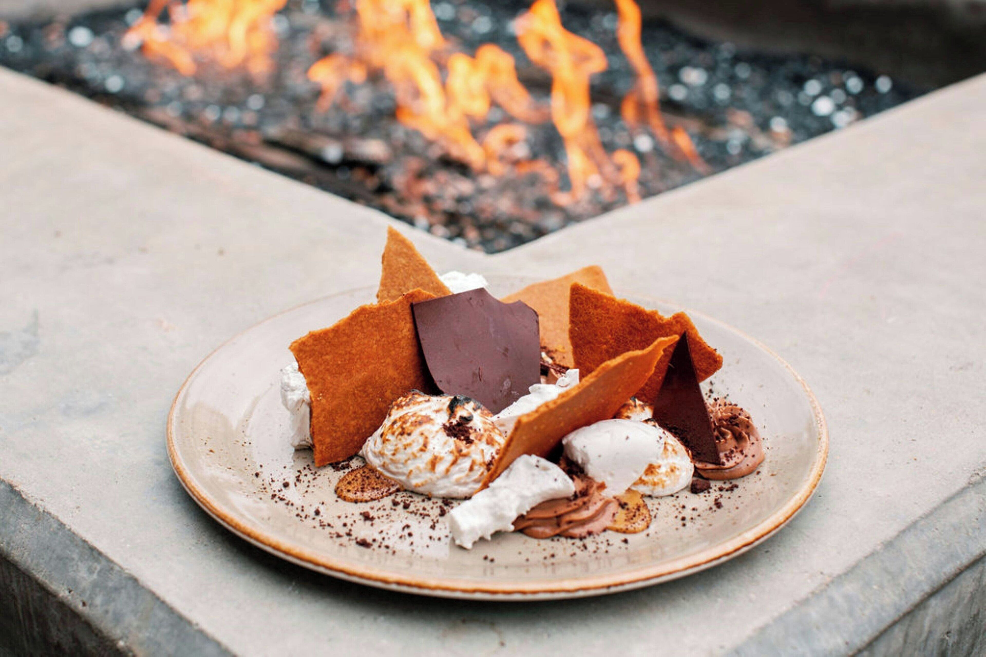 Een dessert op een bord, met een vuur op de achtergrond.