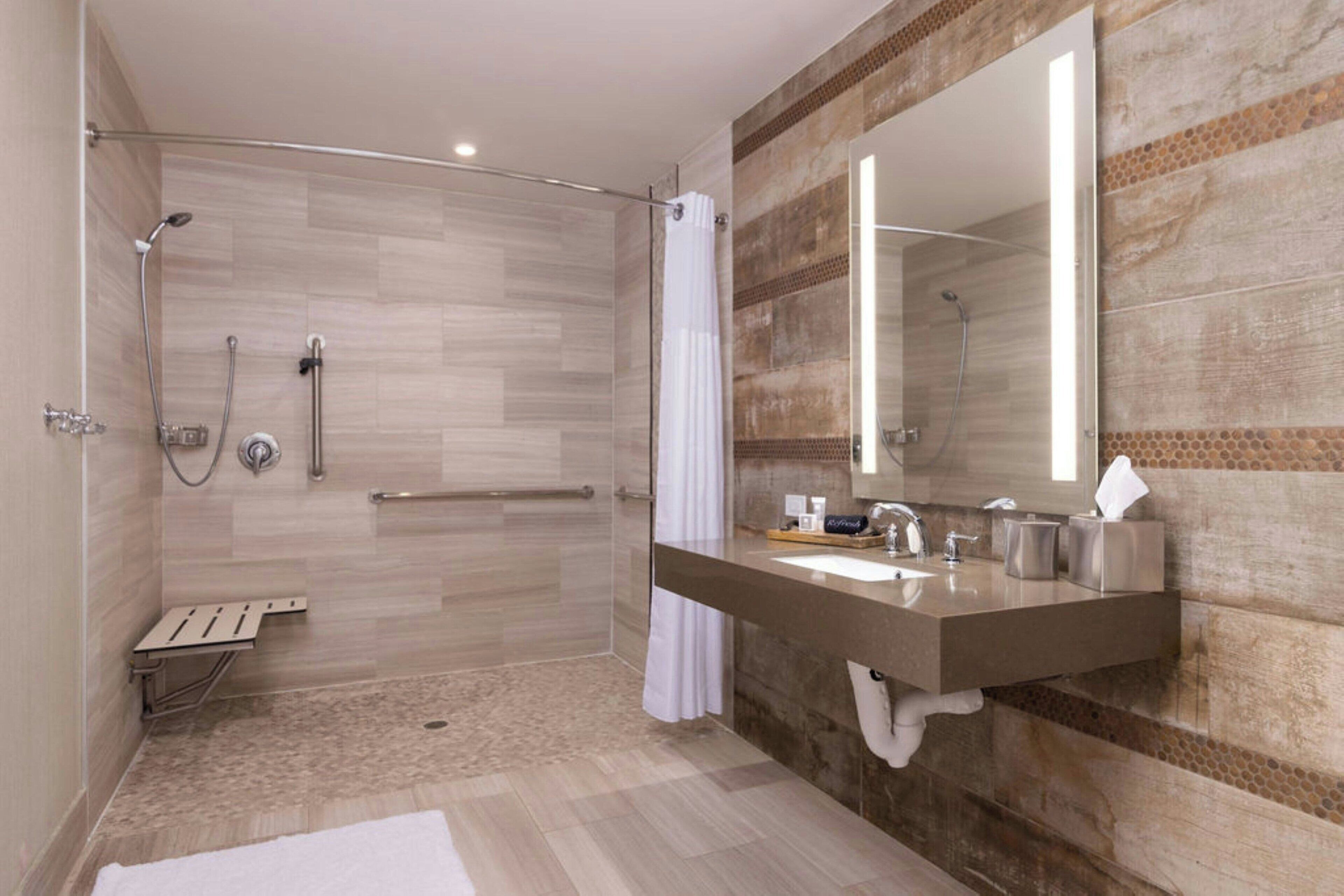 Un baño moderno con cabina de ducha, tocador con espejo y barra para toallas.