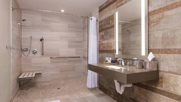 Un baño moderno con cabina de ducha, tocador con espejo y barra para toallas.