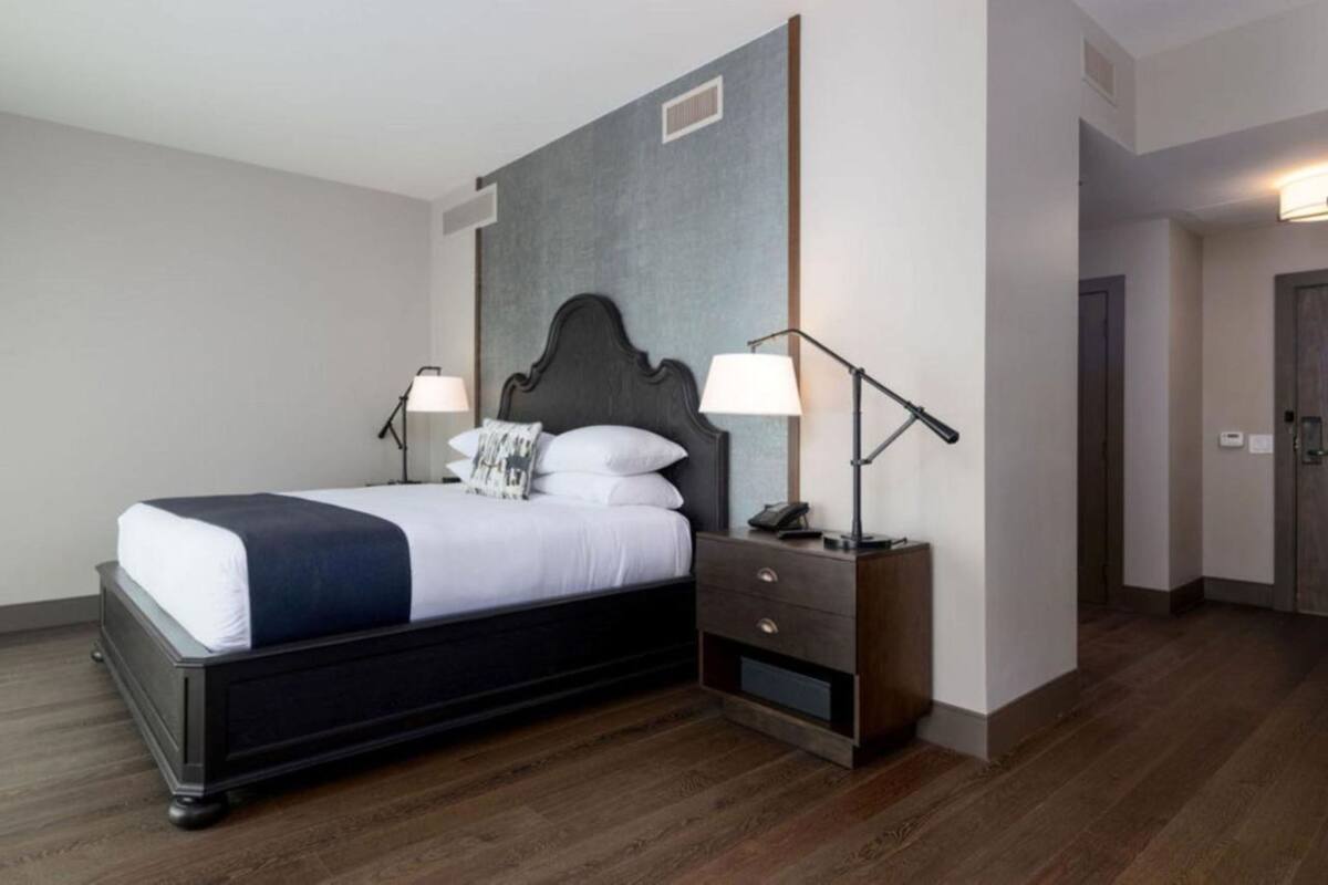 Ett modernt hotellrum med en stor säng, sänglampor, ett nattduksbord och en garderob.